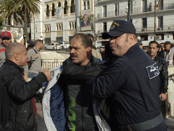 An Algerian policeman detains a trade unionists as they gather outside the People's National Assembly building in the capital Algiers on Sunday to protest the pension reform that is set to be debated by deputies (AFP photo)